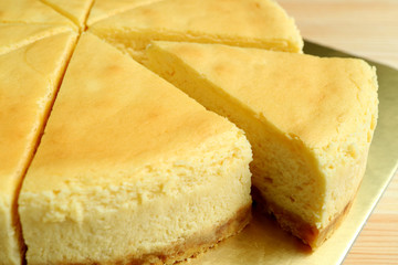 Closed up a piece of creamy yellow plain baked cheesecake cut from the whole cake