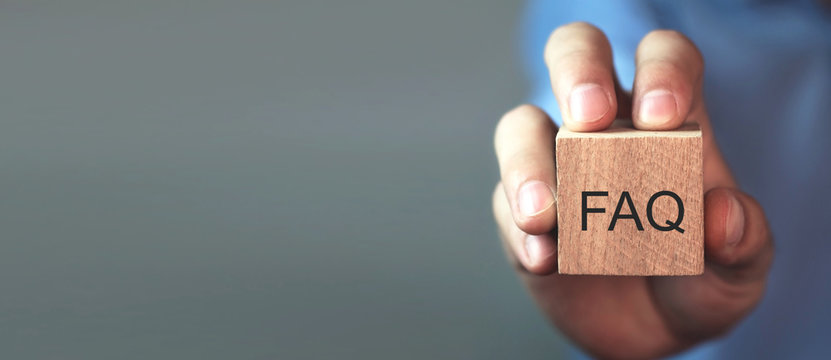 Man Holding FAQ Message On Wooden Cube. Frequently Asked Questions