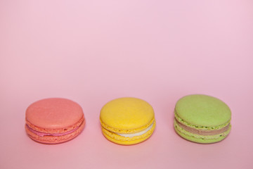 Pink, yellow and green macaroon on pink, pastel colors food background