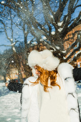 Beautiful redhead woman in white fur coat having fun outdoor