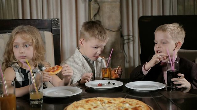 Happy kids eat pizza in the restaurant
