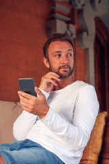 Man sitting on a terrace sofa and using cellphone.