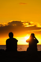 Couple watching the sunset on a beach in Maui Hawaii USA