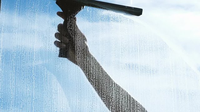 Hand washes the wiper with a dirty window from the outside close-up, slow motion