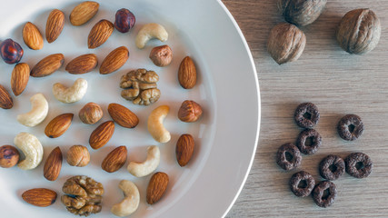 Almonds, Hazelnuts, Walnuts, Cashew Nuts on A White Plate, Three Whole Walnuts, Crunchy Whole Grain Cereals Round Oats on Light Wooden Table. Healthy Organic Snack, Breakfast, Food Ingredients.