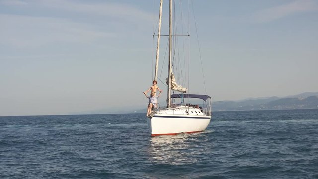 Sail boat during sunny summer weather on calm blue sea water with romantic couple on the deck. Luxury summer adventure, active vacation in Mediterranean sea.