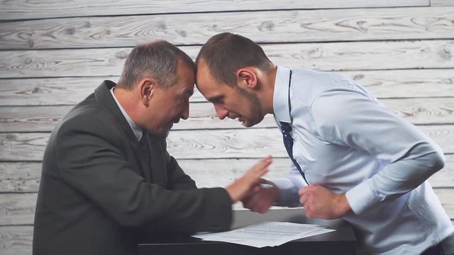 Aggressive angry businessman makes partner or client sign a contract. Concept on the topic of cruel business.
