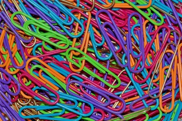 Macro photo of colored paper clips scattered randomly, filling the entire frame.