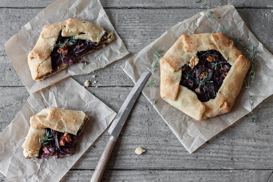 Red onion rustic galettes with fresh thyme on rustic table with handcrafted knife