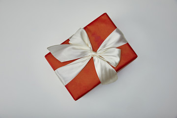 Top view of wrapped gift with white satin ribbon isolated on grey background