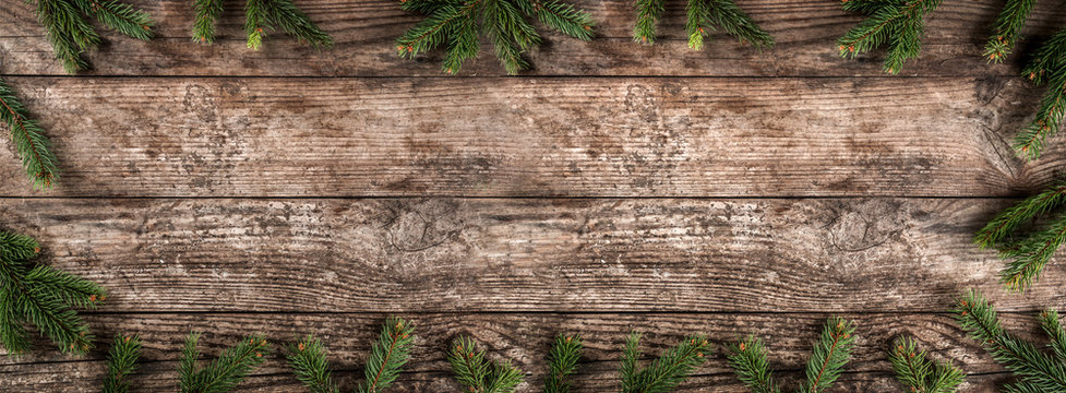 Creative layout frame made of Christmas fir branches, pine cones on wooden background. Xmas and New Year theme. Flat lay, top view, wide composition