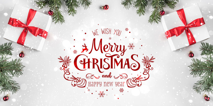 Merry Christmas Typographical on white background with gift boxes, fir branches, red decoration. Xmas and New Year card, bokeh, light. Flat lay, top view