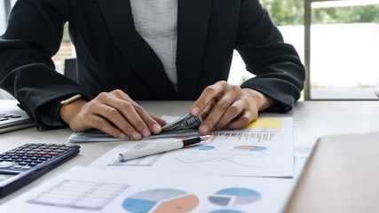 Business woman accountant working and calculating financial data on graph documents, doing finance in workstation