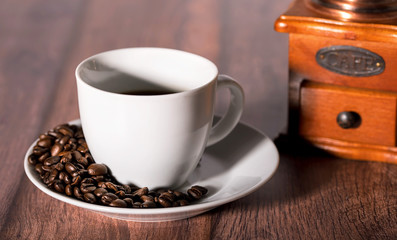 Roasted coffee beans and cup of coffee on wooden table