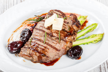 Grilled pork chop steak with dates in honey, rosemary, asparagus and beet salad on wooden background. Hot Meat Dishes. Top view, flat lay