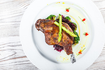 Grilled pork chop steak on the bone with asparagus and broccoli on light wooden background close up. Hot Meat Dishes. Top view