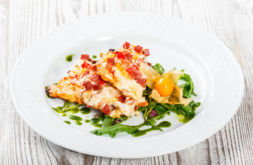 Grilled chicken steaks with cheese, vegetables, ham and salad from arugula, physalis  on wooden background. Hot Meat Dishes. Top view, flat lay