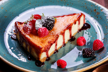 Delicious cheesecake with fresh berries and mint on dark wooden background, sweet dessert. Vanilla cheese cake. Top view