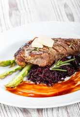 Grilled pork chop steak with dates in honey, rosemary, asparagus and beet salad on wooden background. Hot Meat Dishes. Top view, flat lay