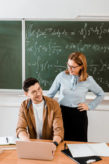 Female teacher looking at young student and smiling in classroom