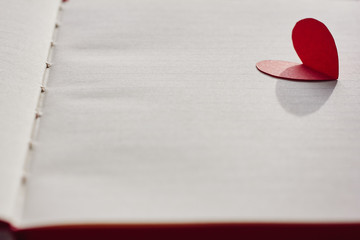 Opened blank notebook and red paper heart