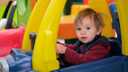 Fototapeta na wymiar Toddler boy driving a sit and ride car.