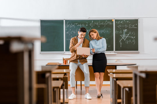 Young student standing with female teacher and looking at laptop - Powered by Adobe