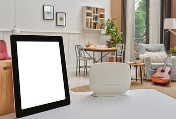 Close up router and tablet on the table, modern living room decoration background. Wireless, modem, internet concept. Price information concept for tablet.