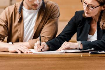 cropped view of female teacher checking exam results of male student in classroom