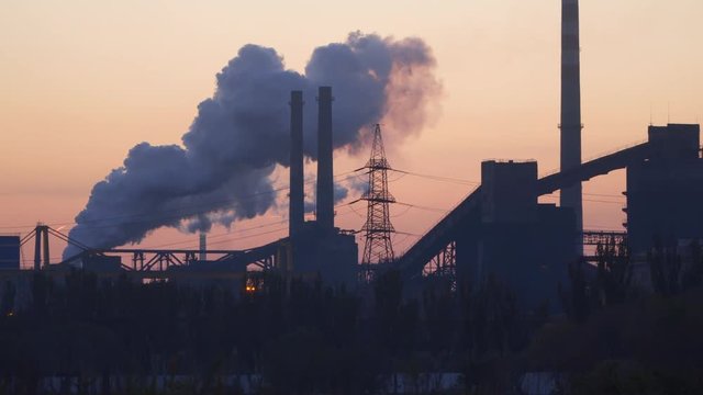 Smoke from factory chimneys against predawn sky.