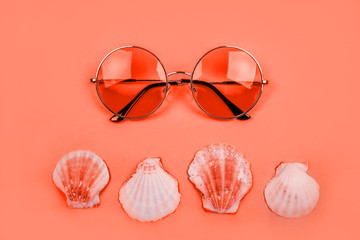 Obraz premium Summer flatlay with round gradient sunglasses and sea shells on the bright living coral backfround.