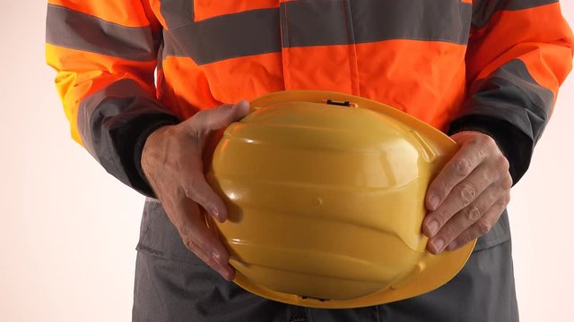 Nervous construction foreman holding yellow hard hat, close up of hands
