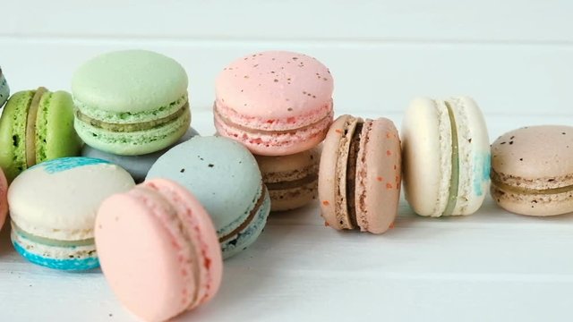 Multicolored macaroons or macarons lie on a white wooden background, a row of almond cookies