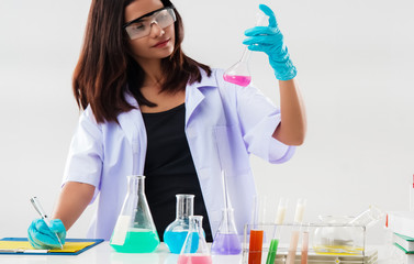 The chemist in protective eyeglasses and blue rubber glove,working by test tube with reagent in...