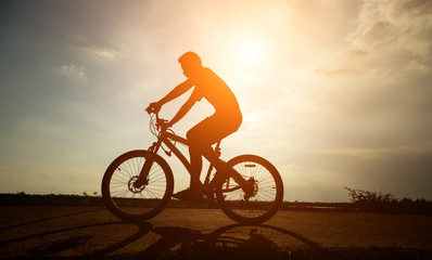 Fototapeta na wymiar Silhouette young man riding a bicycle
