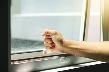 Hand holding glass window latch handle.