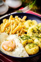 Fried egg served with potatoes and yellow beans.