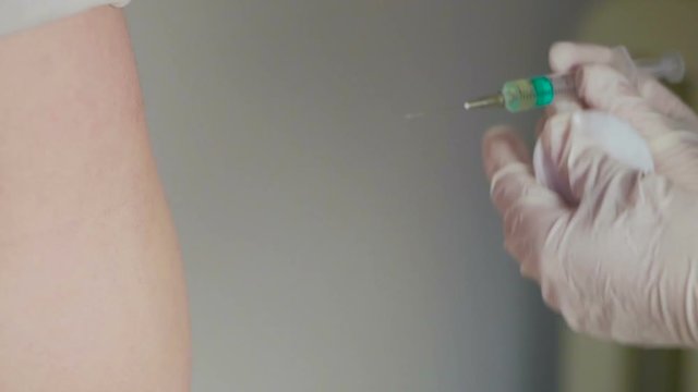 Close-up of the hand of a medic administering an intramuscular injection to a patient.