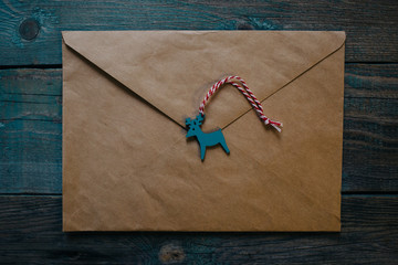 letter to Santa Claus, envelope with wooden Christmas decor in the form of wax seal, flat lay on dark wooden background