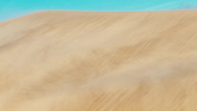 desert sand dunes with stormy winds and abstract sand movement and formations while the wind blows the grains and streaks in the air at playa ingles gran canaria spain