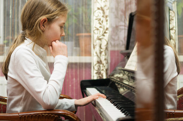 Little girl learning to play the piano. © M-Production