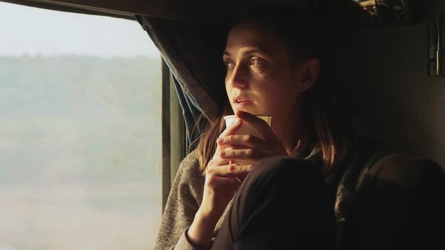 Young women drinking water while looking out of a asian train window