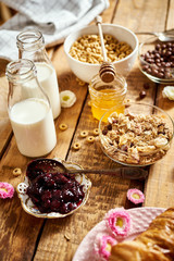 Healthy morning breakfast with different types of breakfast cereal with honey marmalade croissants and milk on old wooden table