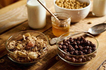 Healthy morning breakfast with different types of breakfast cereals with a spoon, honey and milk on an old wooden table
