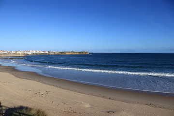 beach of gâmboa in Peniche with  the city in the background
