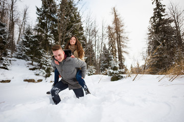 Fototapeta na wymiar Happy man piggybacking woman in the snow