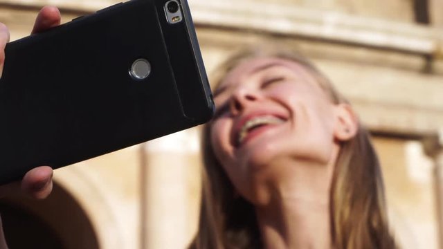 A girl takes a selfie near the Colosseum in Rome. She smiles and poses. Close-up. 4k