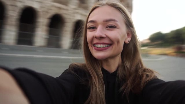Happiness. The girl is spinning near the Colosseum in Rome. Tourist makes selfie. She's happy. Slow motion.