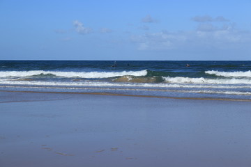 waves crashing on the beach with surfers in the background
