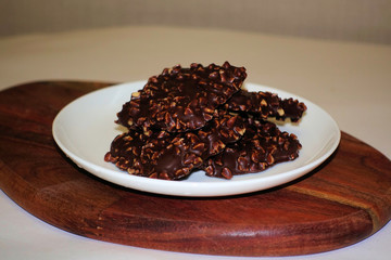 Chocolate square biscuits with nuts on a white round plate.